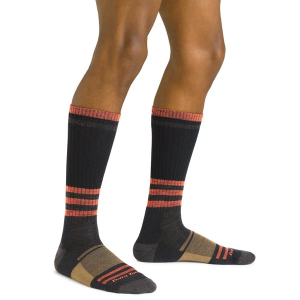 Piernas de un modelo con el calcetin altura de bota y color negro con rayas salmon y dorado.