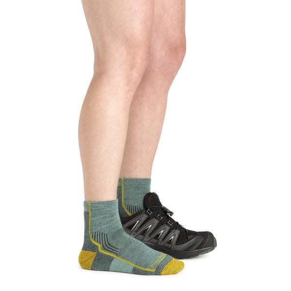 Dos piernas de modelo una con un calcetín verde y amarillo  y la otra con una zapatilla negra