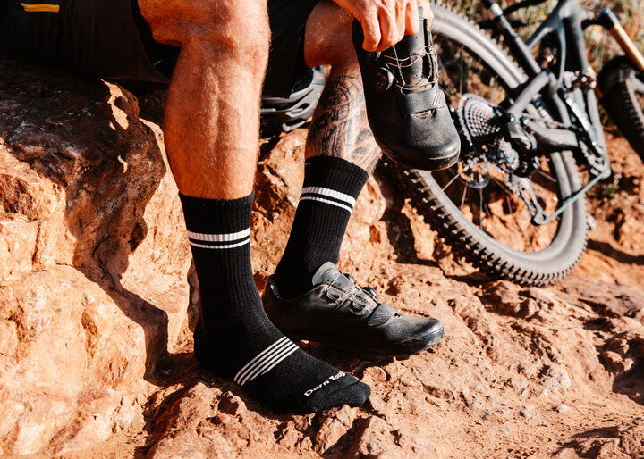 Ciclista en la montaña con calcetines Darn Tough calzando una zapatilla