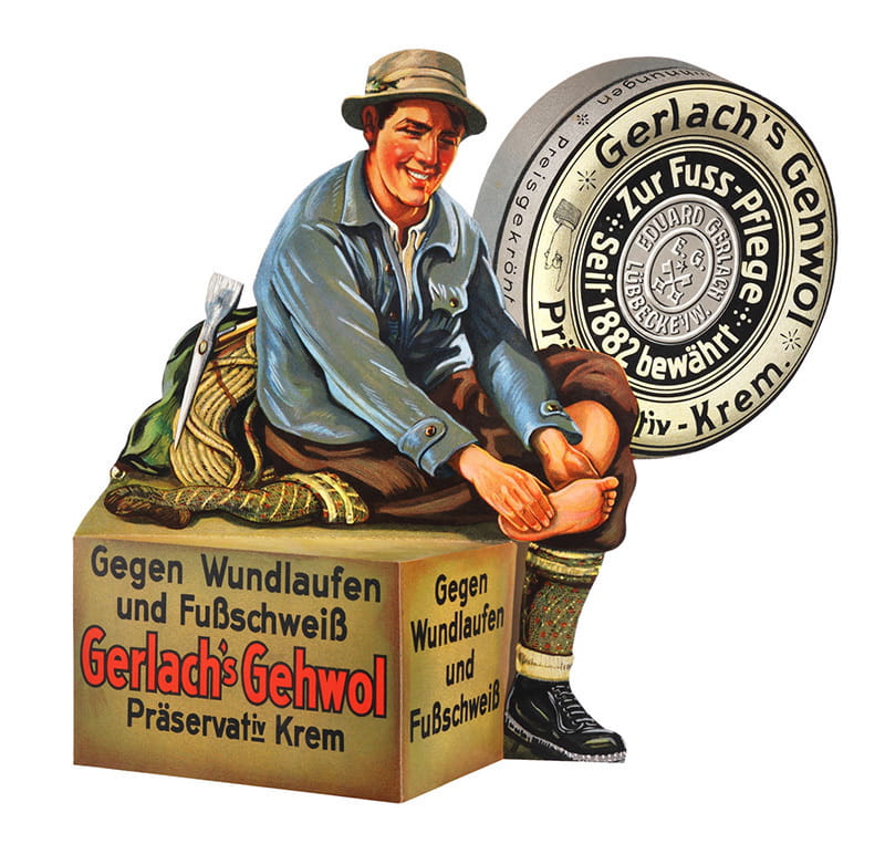 Anuncio de la crema Footcream de Gehwol de un montañero masajeando un pie sobre una caja y de fondo la crema footcream