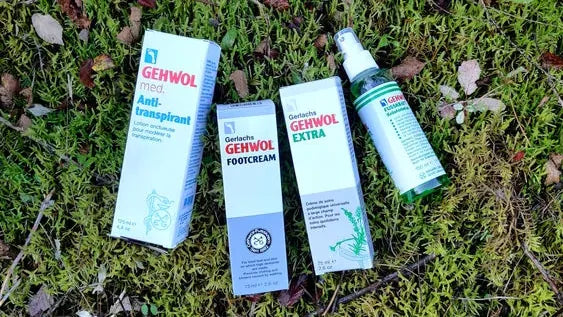 Cuatro productos para el cuidado de los pies sobre un fondo de musgo verde.