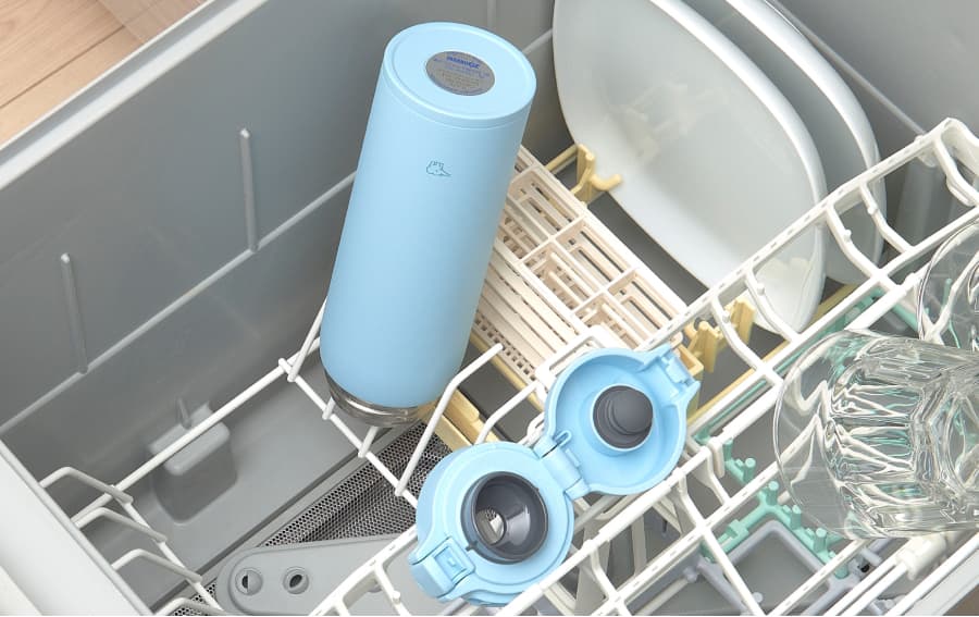 Botella Zojirushi SU-BA desmontada y puesta en el lavavajillas vertical con dos platos blancos y dos vasos 